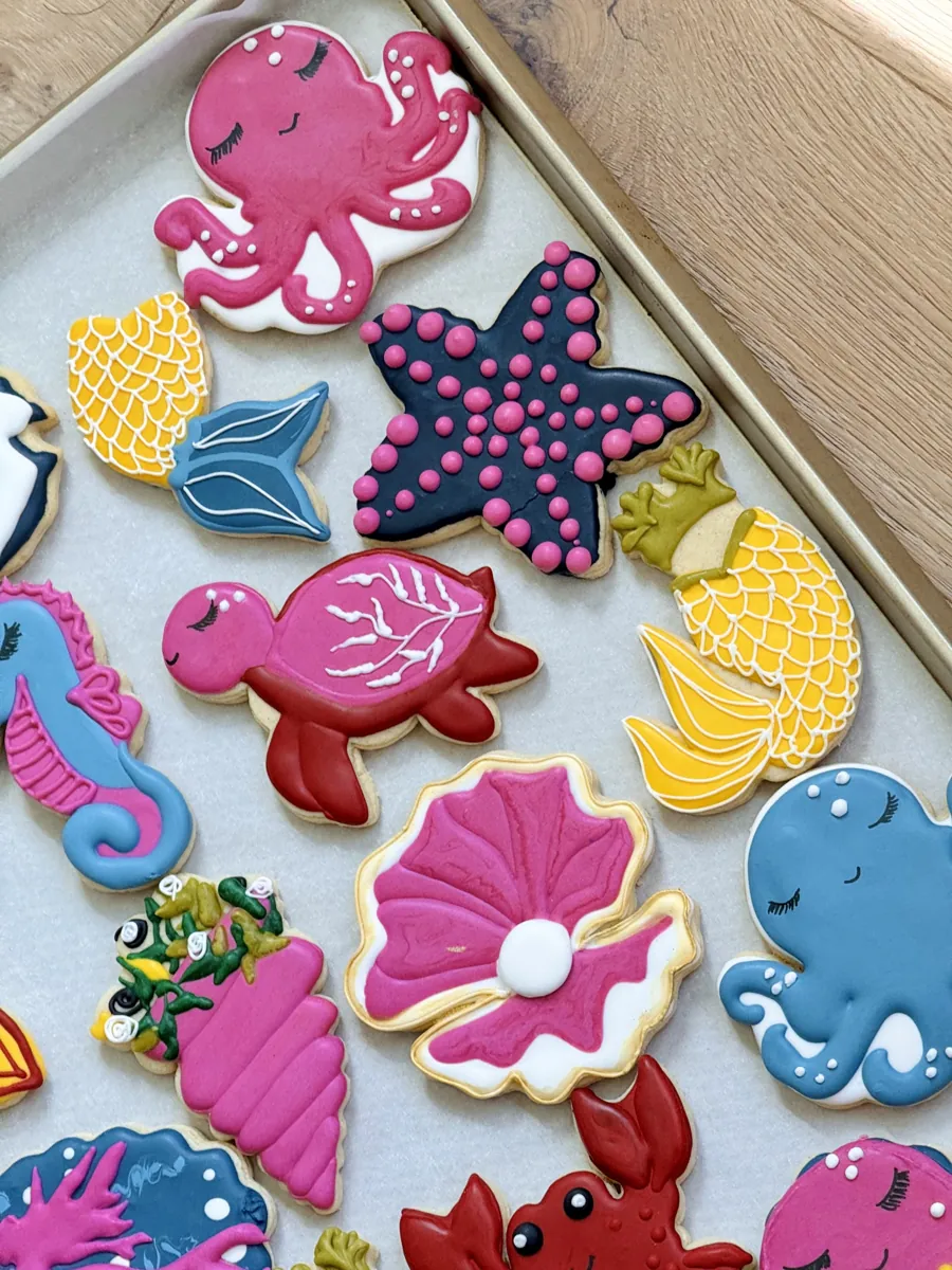 Ocean birthday cookies with pink octopus, sea turtle, starfish, pearl shell and mermaid tails in pink, blue and yellow