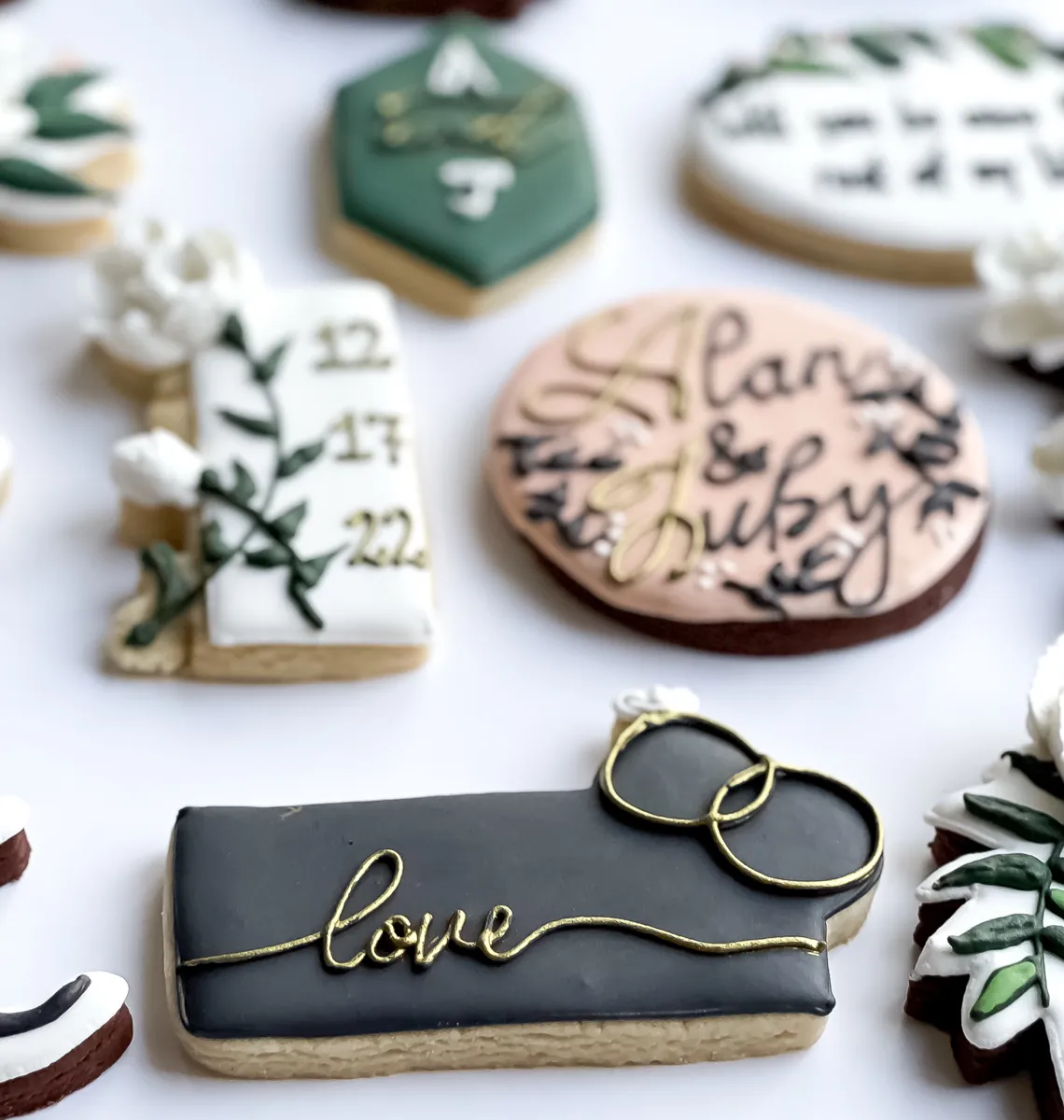 Elegant wedding cookies in black, white and sage green with gold lettering, a love cookie with wedding rings, a date cookie and a monogram